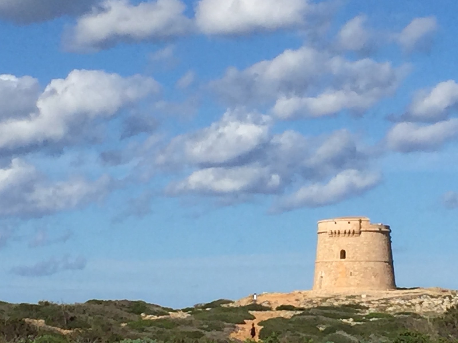 A hilltop fort beneath wispy clouds